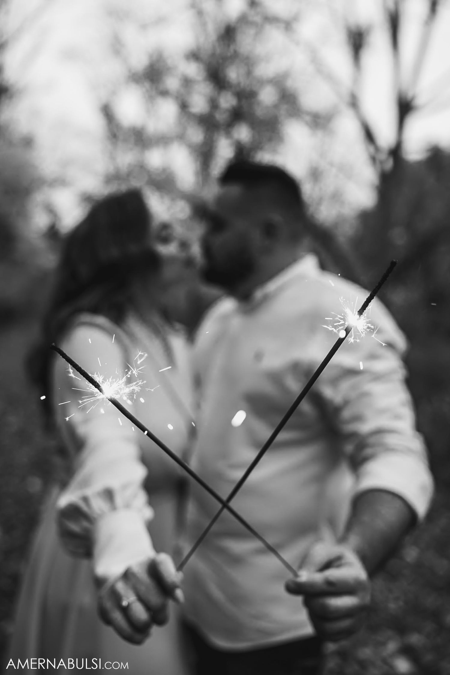 A black and white photo of sparklers creating light trails during an engagement shoot.