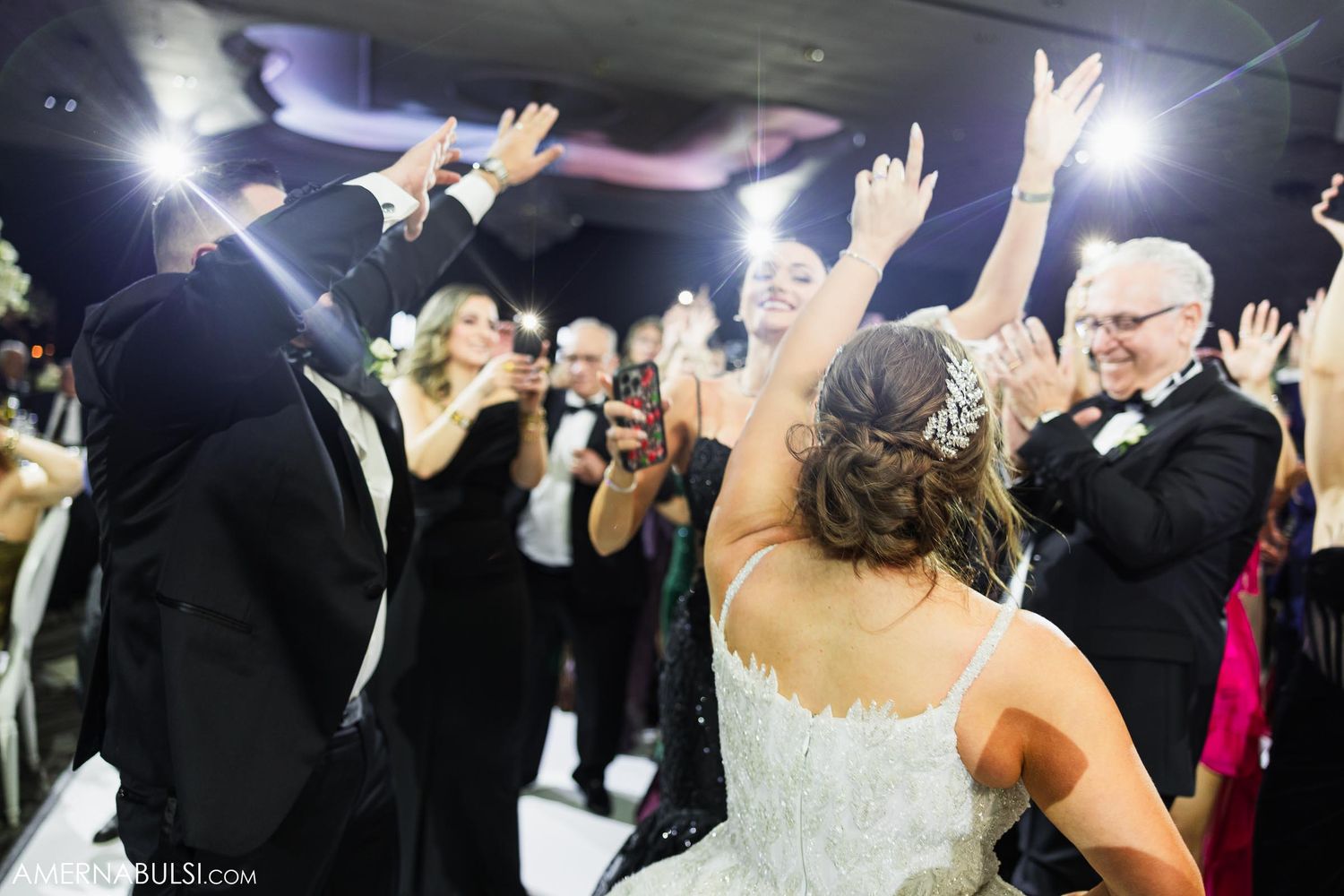 Wedding reception dance floor with guests celebrating under bright spotlight illumination.