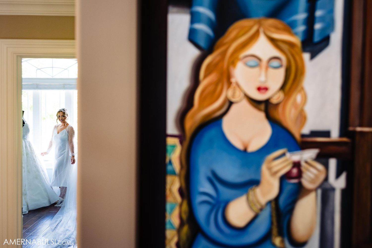 A stained glass artwork in blue frames a distant view of flowing white fabric through a doorway.