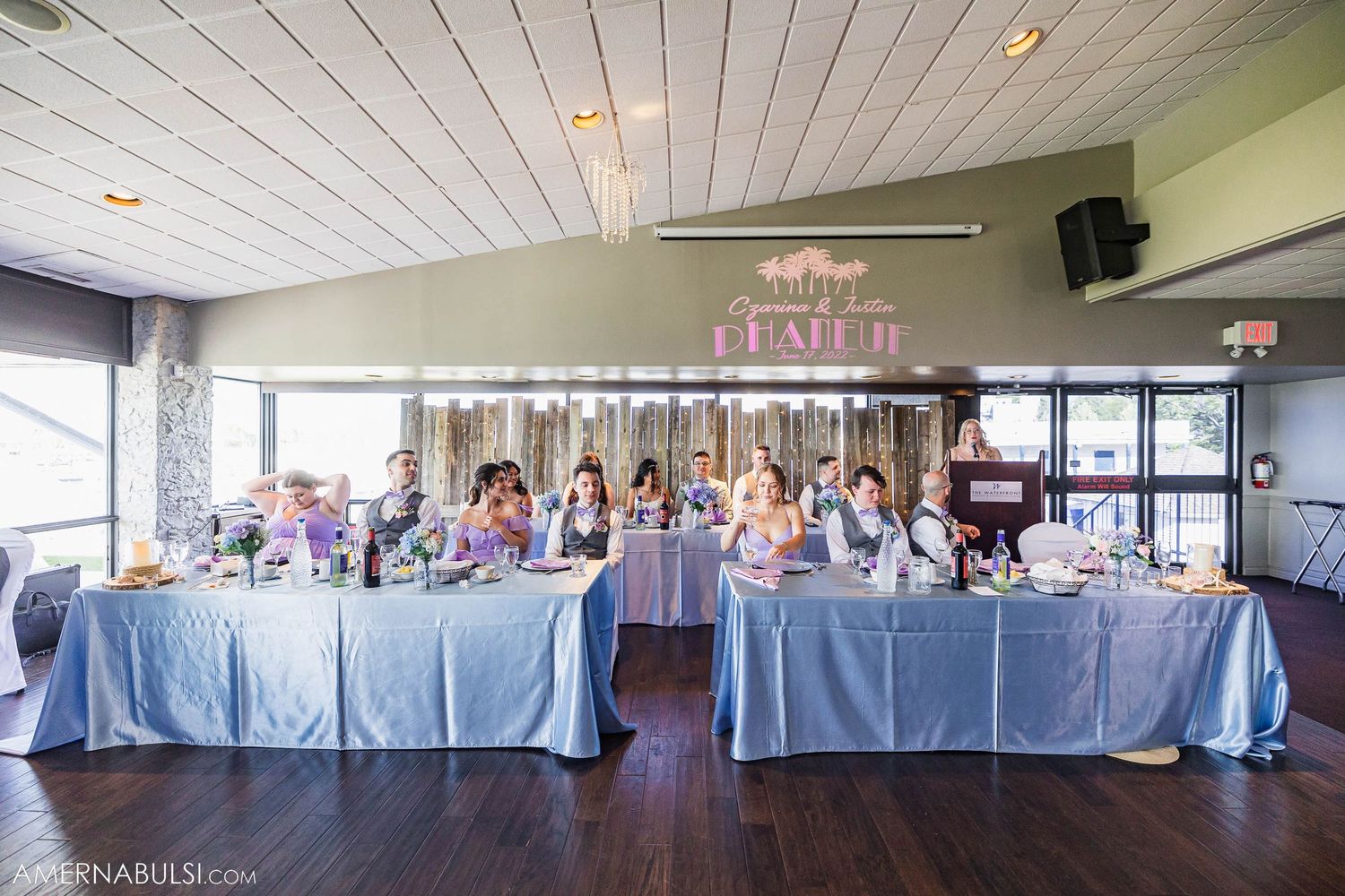 An elegant wedding reception venue with blue tablecloths and white draped ceiling decor.