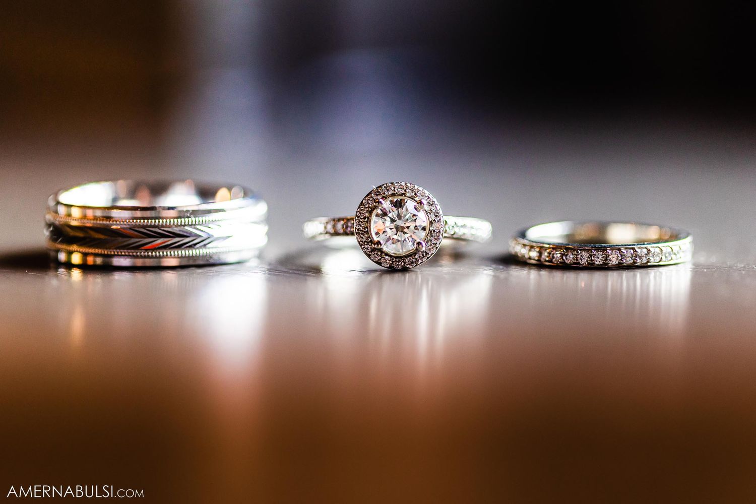 Close-up of three elegant wedding rings displayed on a dark surface.