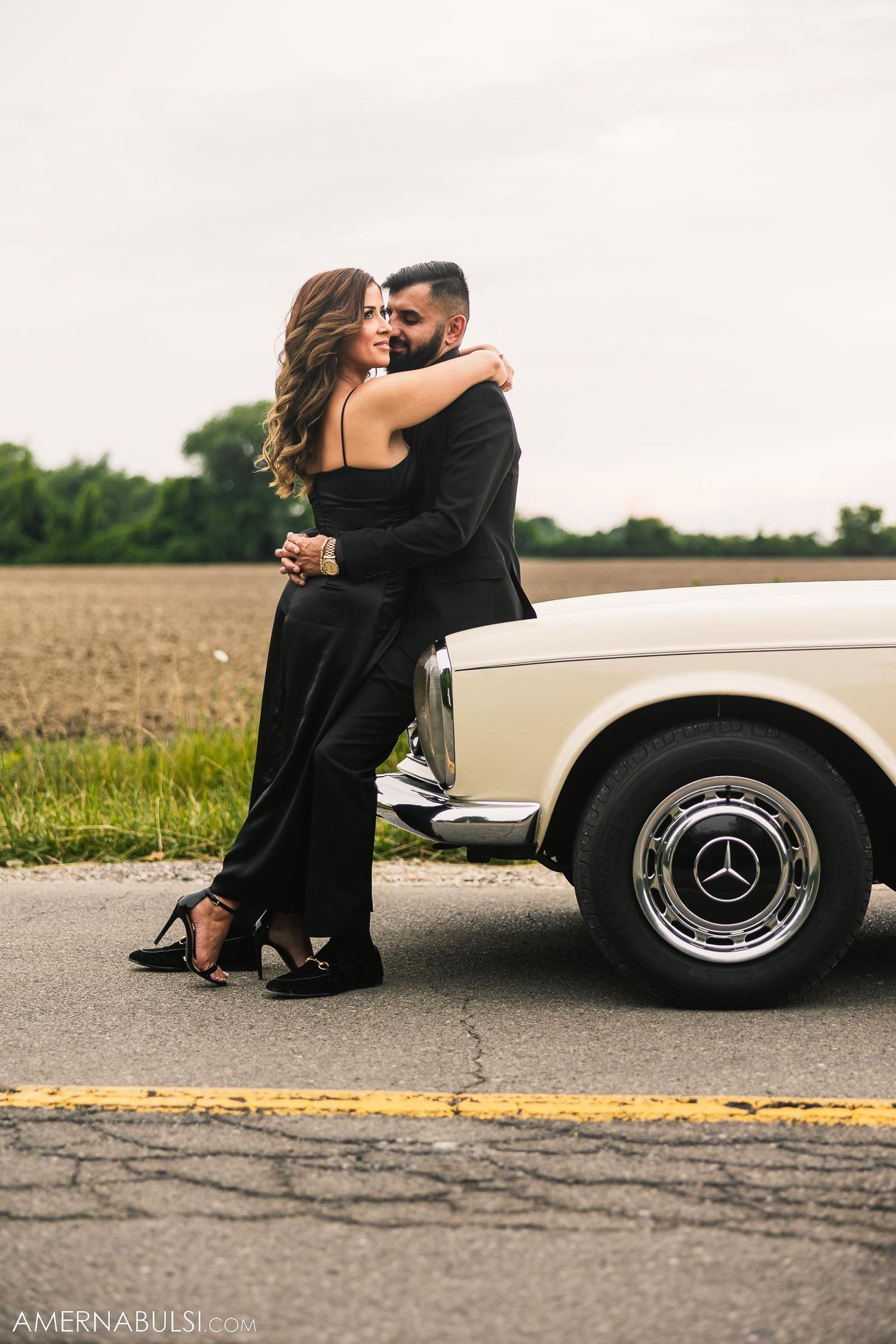 Romantic moment captured beside classic white Mercedes-Benz on country road.