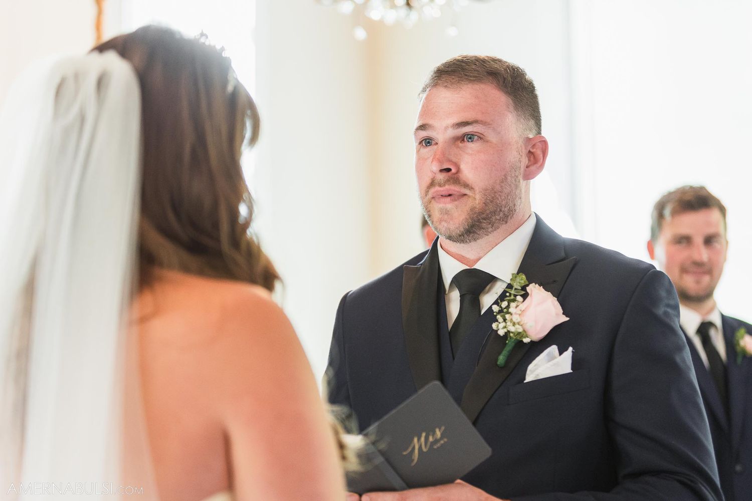 Close-up shot of wedding ceremony vows being exchanged in an elegant indoor venue.