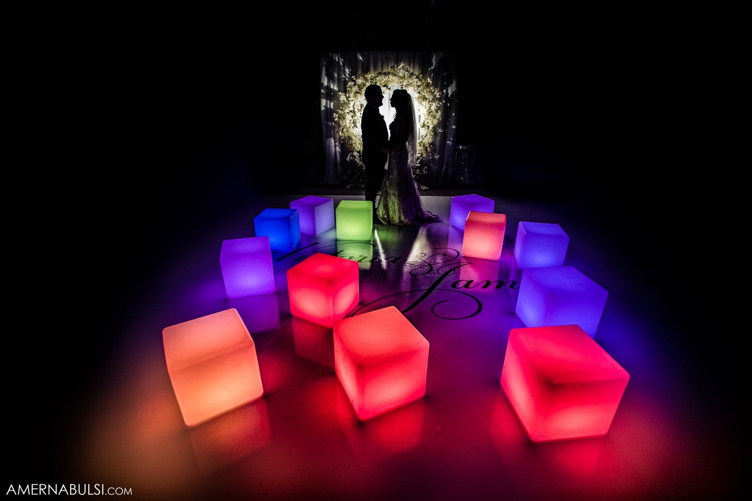 A sequence of illuminated LED cube seats glowing in vibrant colors of red, blue, and purple against a dark background.