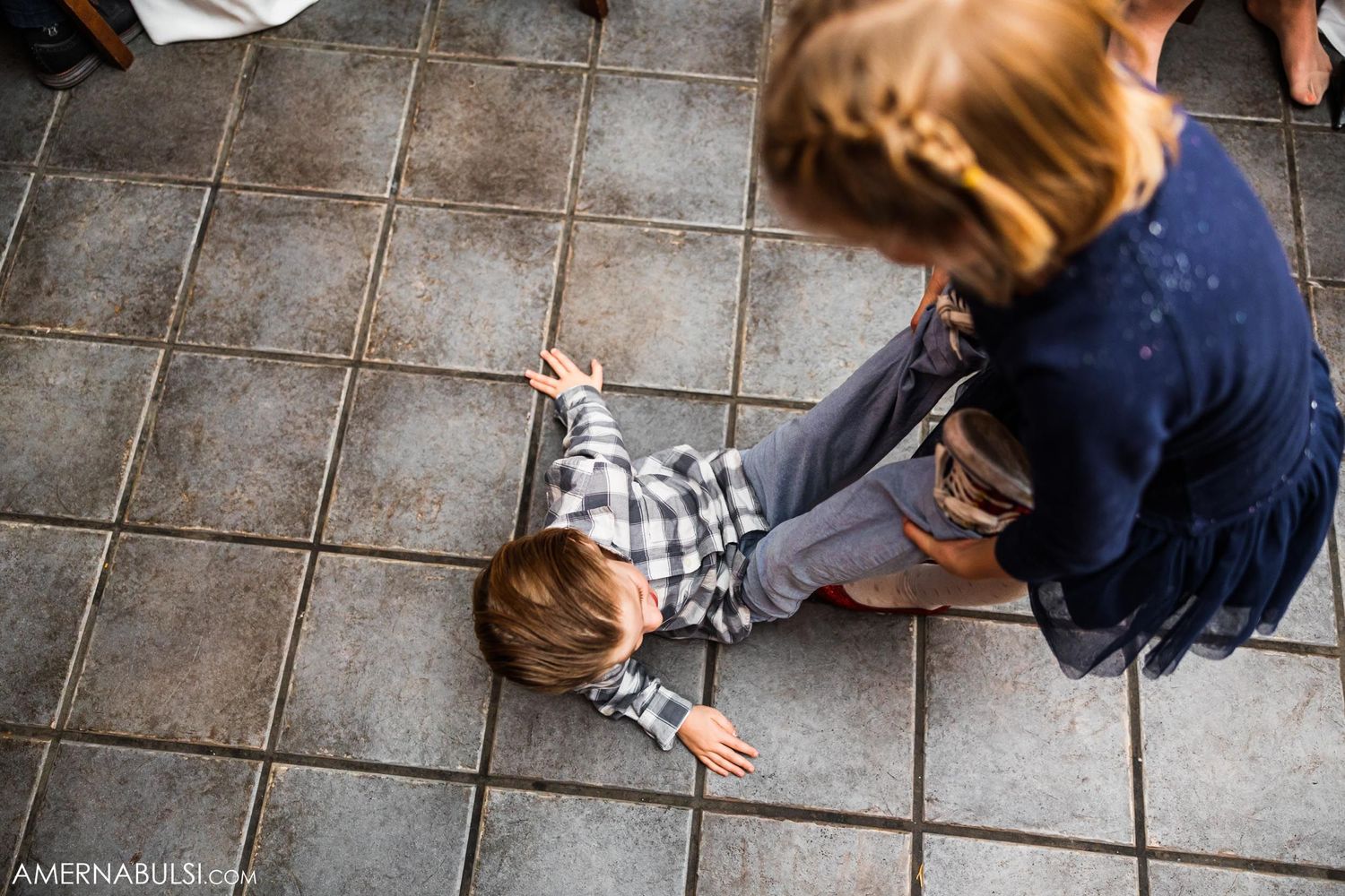 Young guest playing on tiled floor during wedding reception.