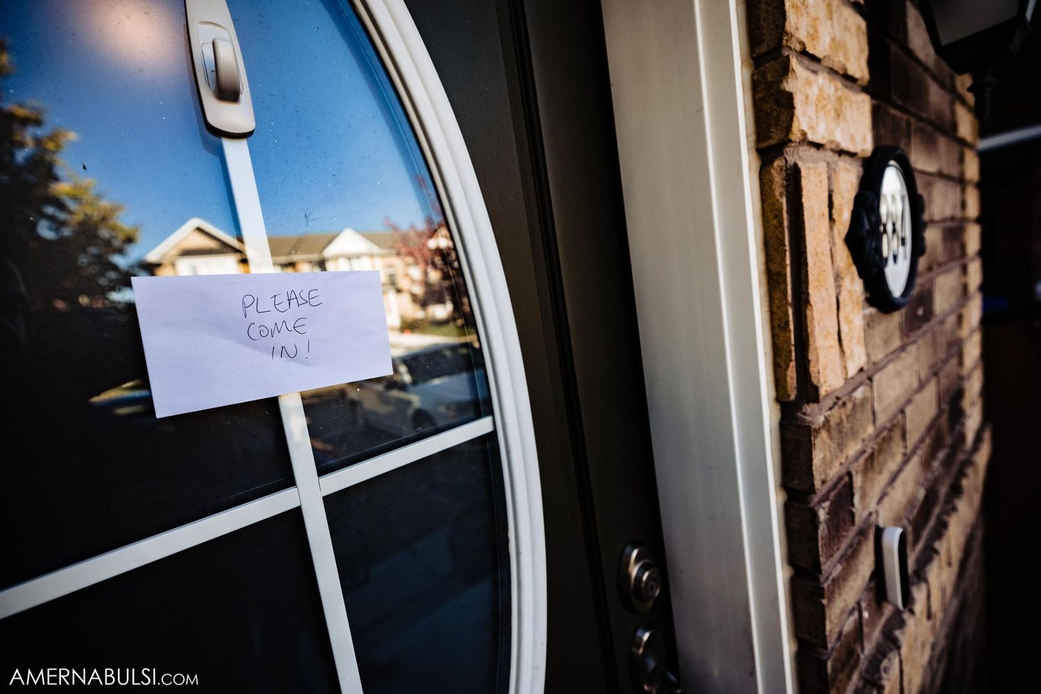 Handwritten note attached to glass door with brick exterior wall visible.