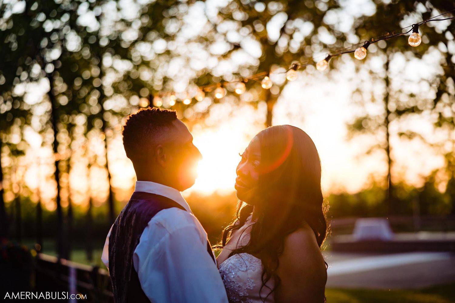 Romantic silhouette of a couple embracing during golden hour sunset with trees in the background.