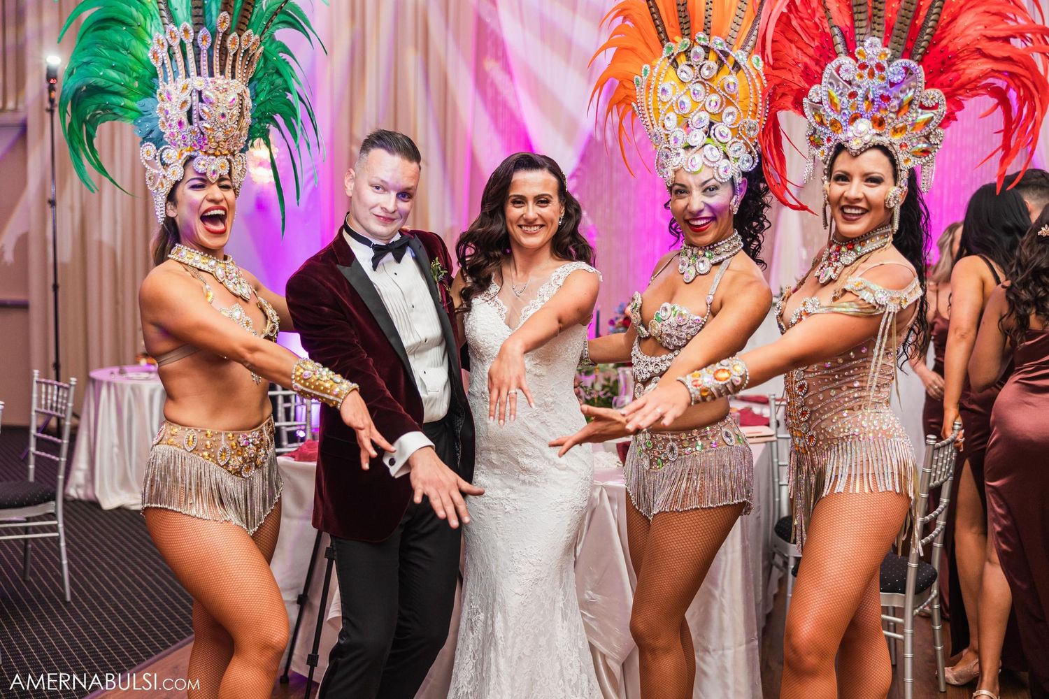 Wedding celebration featuring showgirls in colorful feathered costumes with the newlyweds.