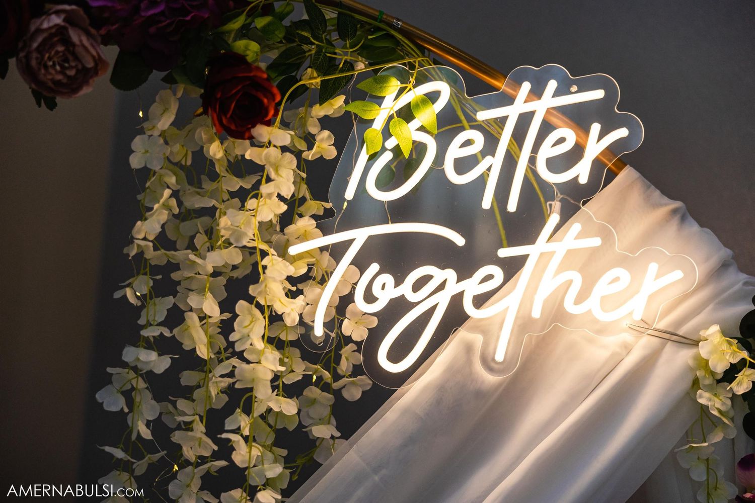 Illuminated neon sign reading 'Better Together' with floral decorations.