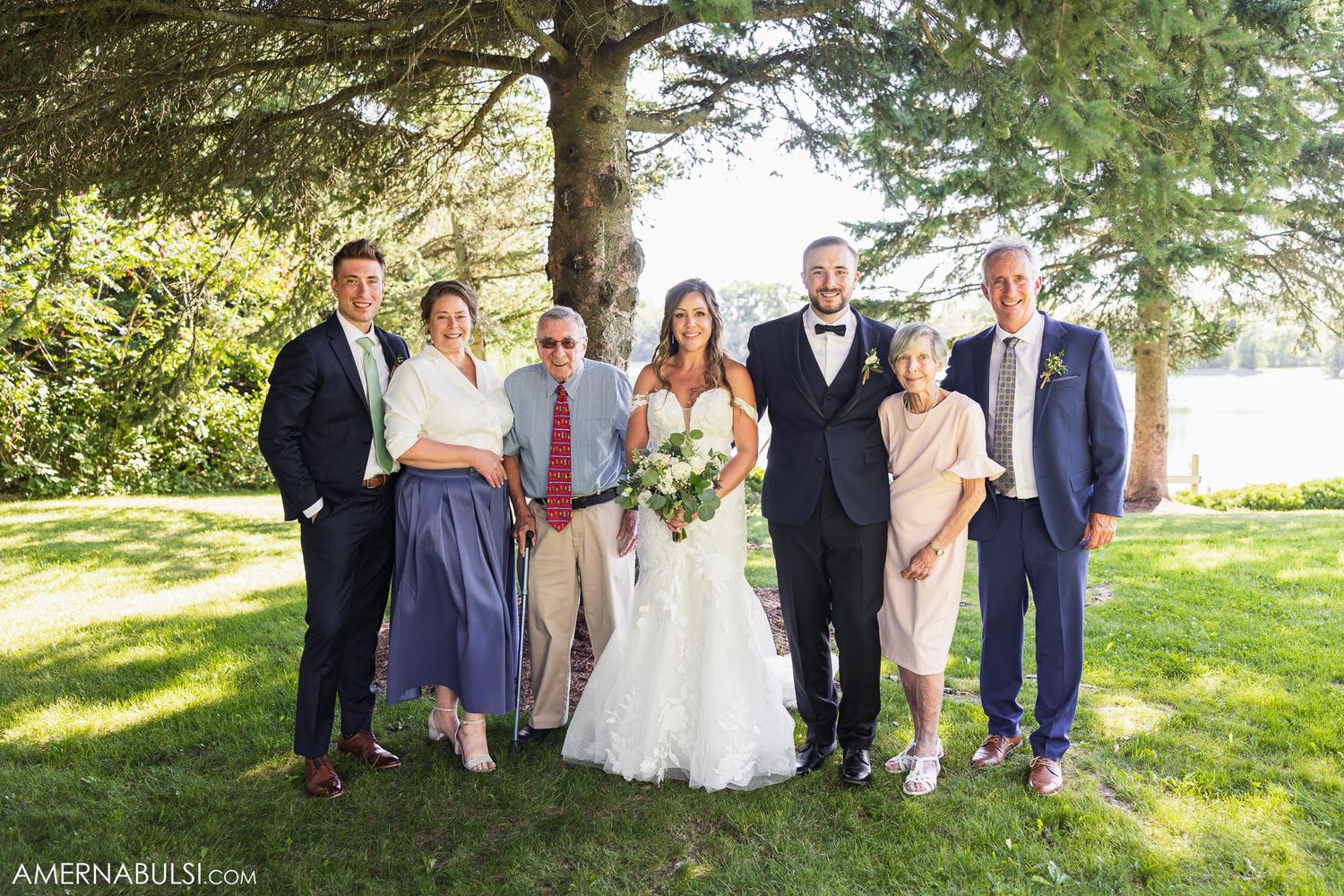 Small wedding party group photo taken outdoors with natural sunlit background.