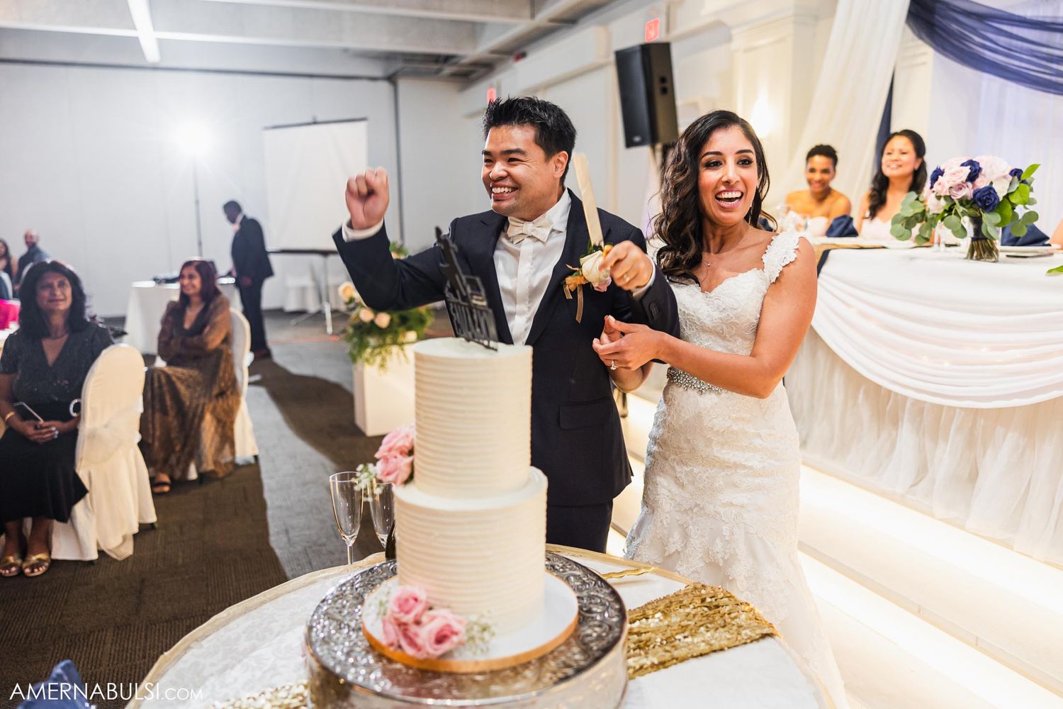 Newlyweds celebrate with excitement after cutting their wedding cake at the reception.
