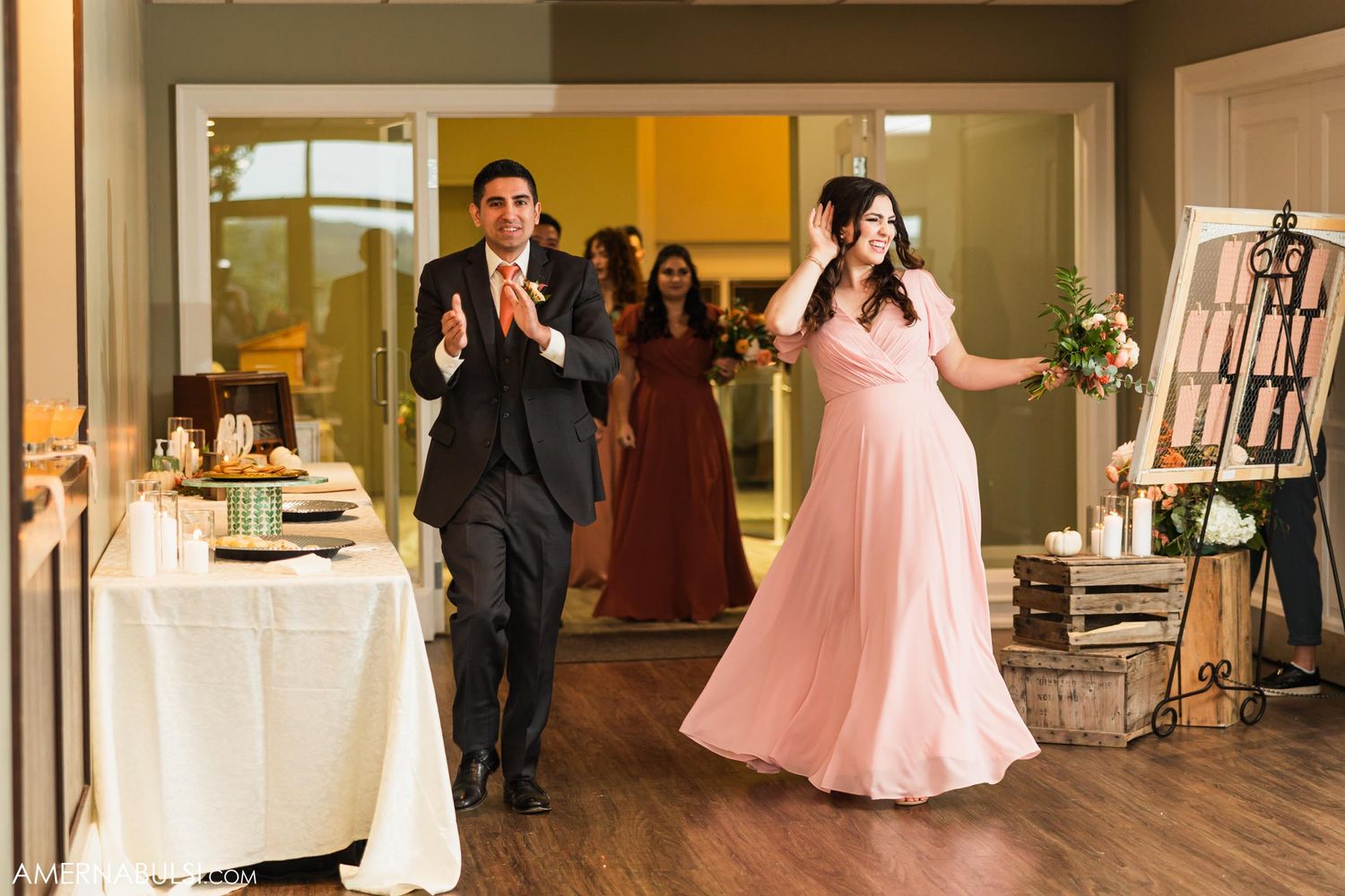 Bridal party members enter reception venue with celebratory gestures.