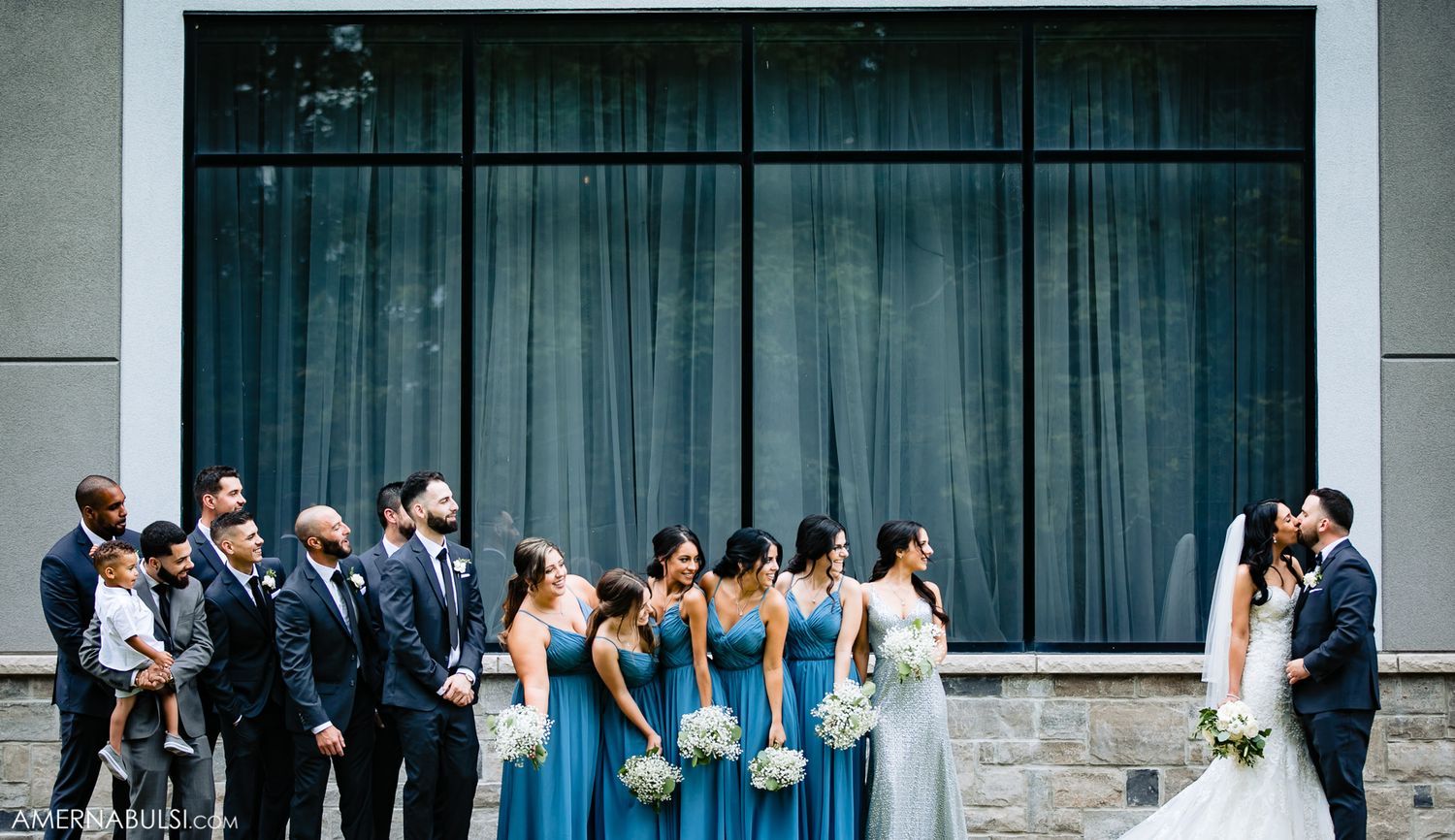 Wedding party in blue and white attire posed together outdoors.