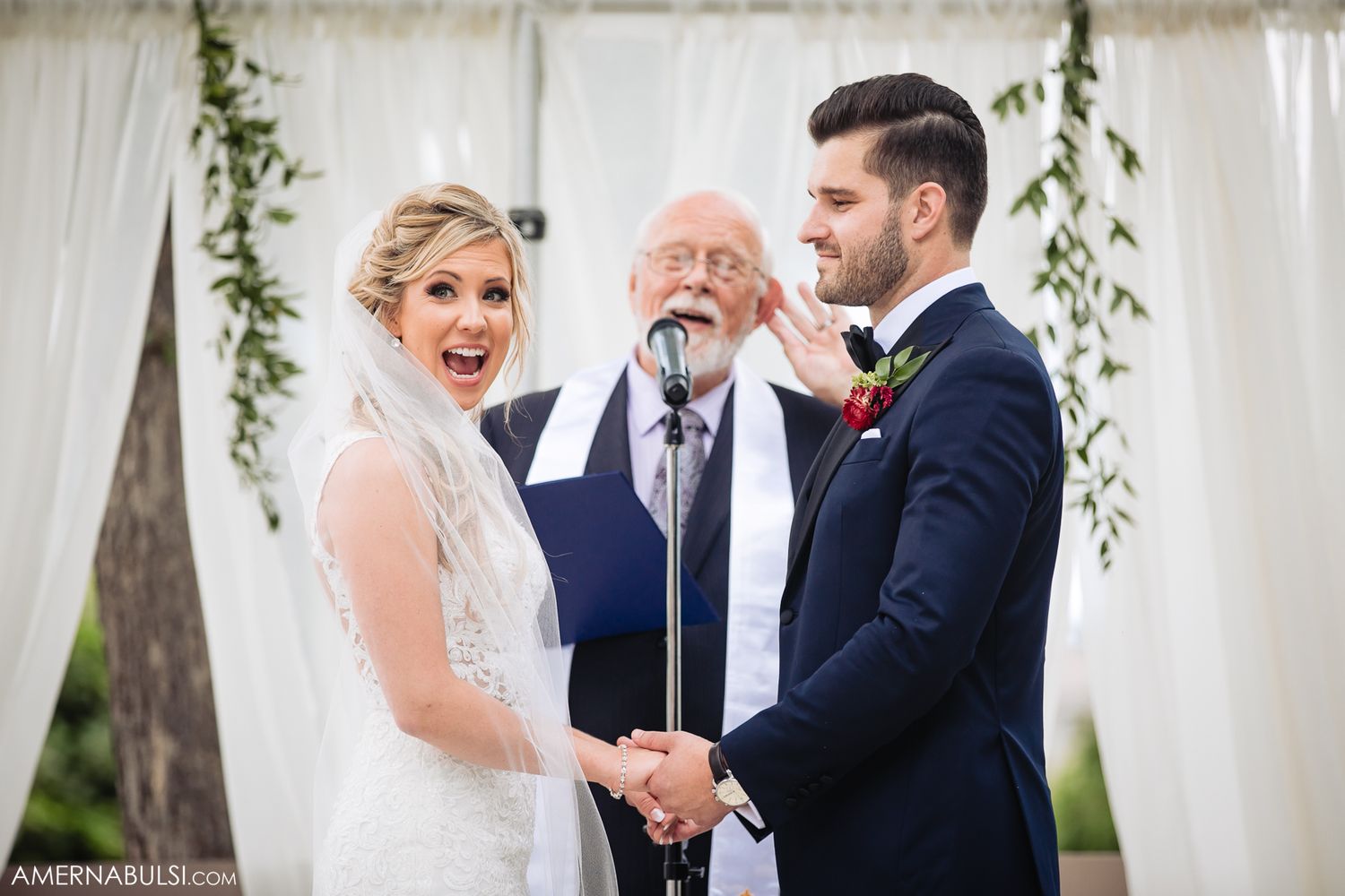 A romantic wedding ceremony moment with hanging greenery decor and elegant white florals.
