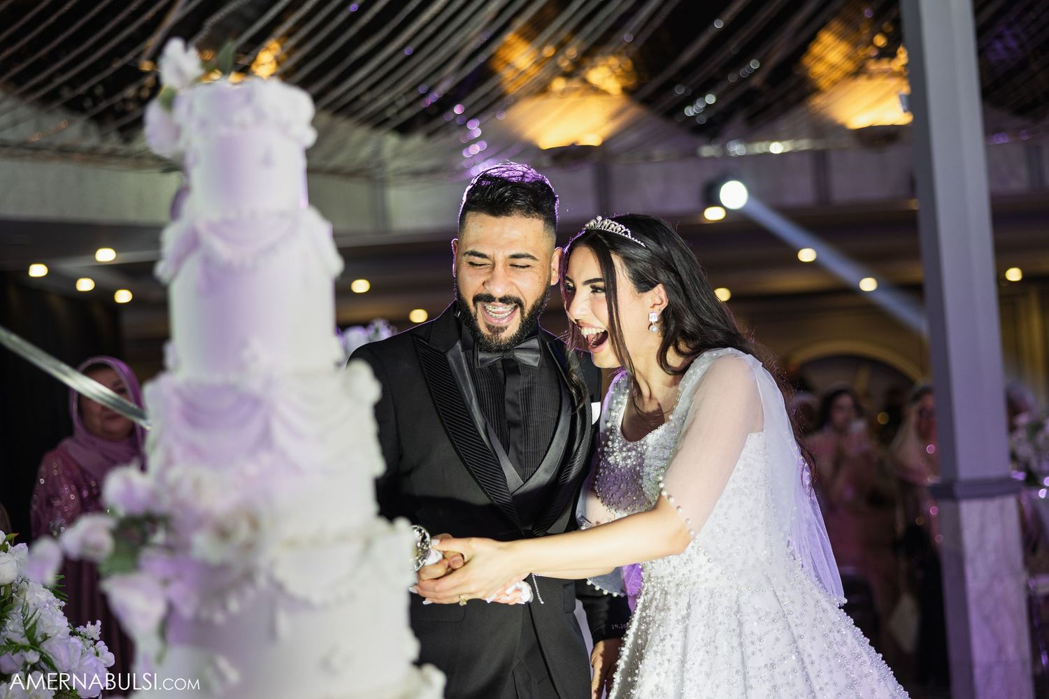Wedding guests dance and celebrate on a reception dance floor under elegant lighting and decorations.