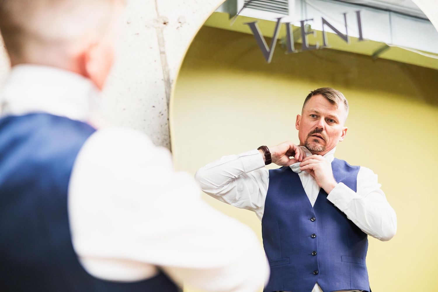 Reflection shot of person adjusting tie in mirror while getting ready.