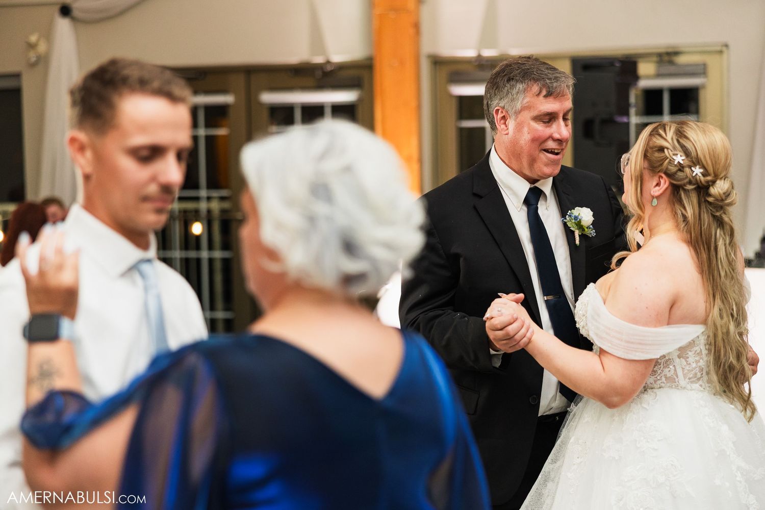 Couple sharing their first dance at a wedding reception with guests watching from the sidelines.