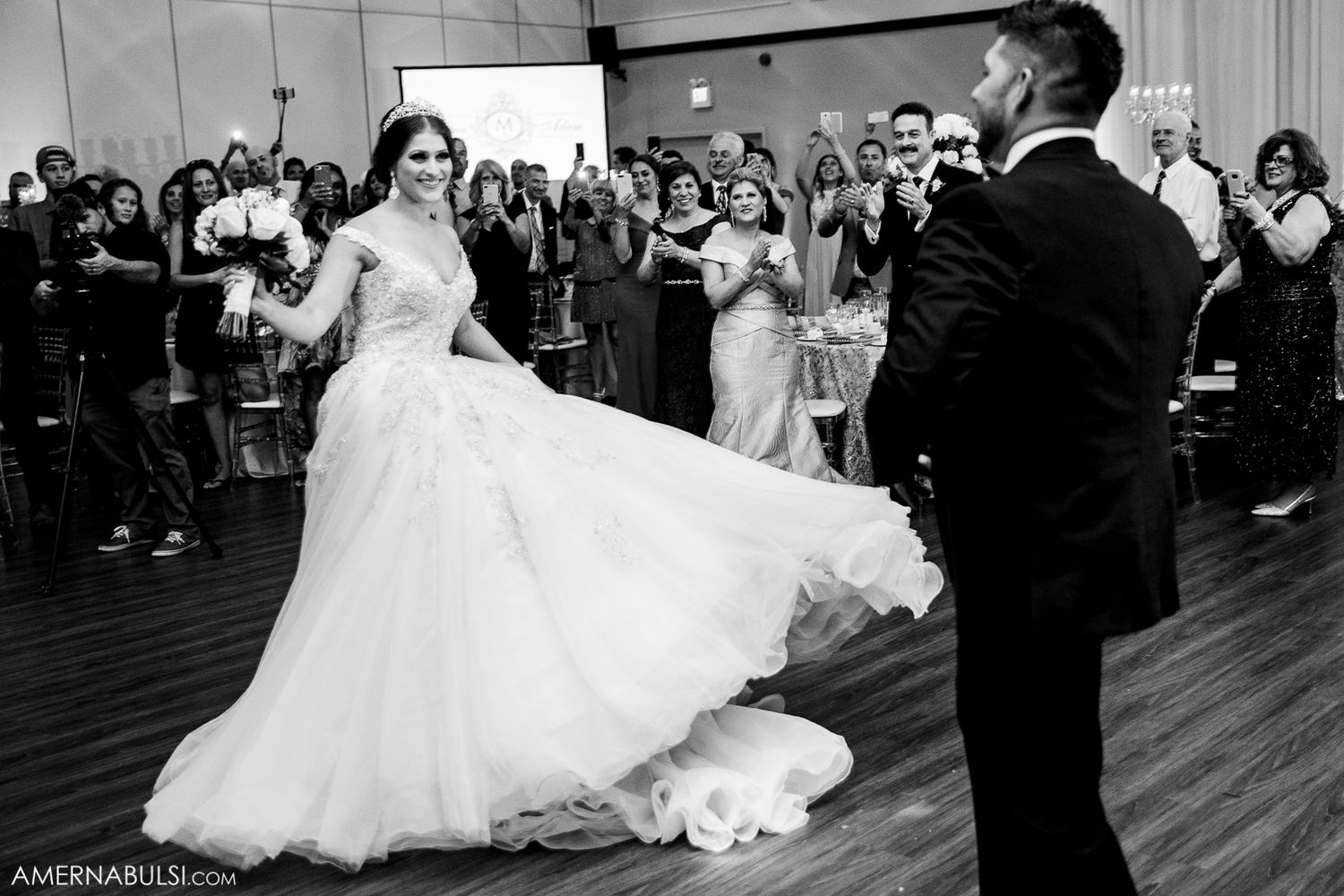 Wedding couple dancing surrounded by guests on a wooden dance floor during their first dance celebration.
