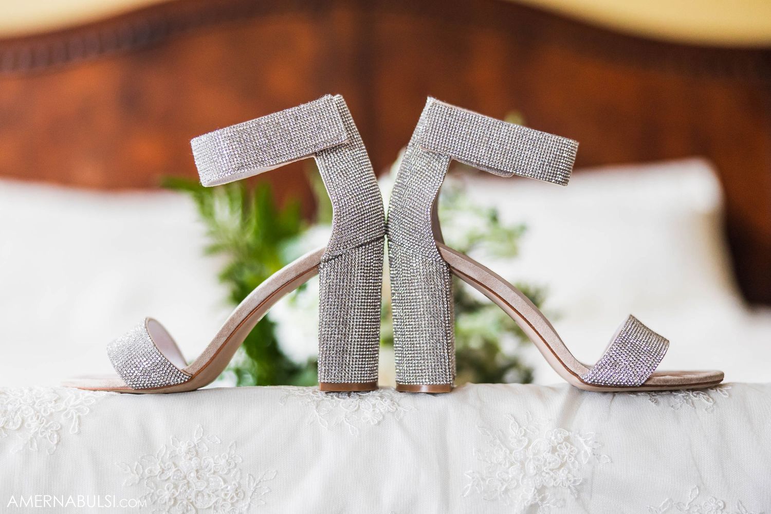 Silver sparkly wedding heels positioned together on white lace surface.