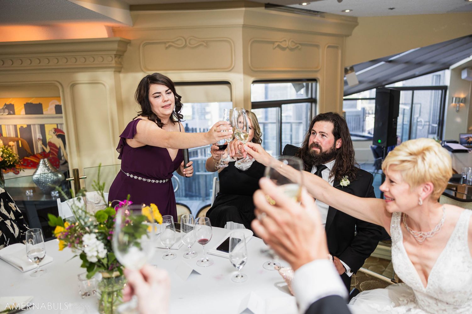 Guests raising glasses in celebratory toast during formal dinner event.