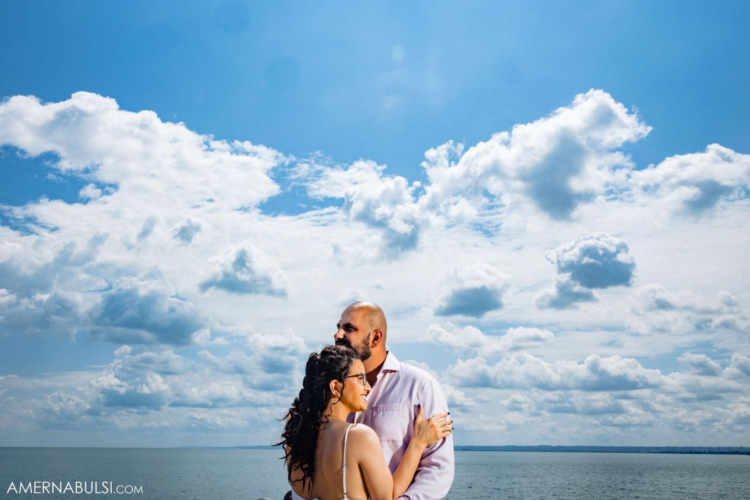 Romantic silhouette against dramatic blue sky with puffy white clouds.