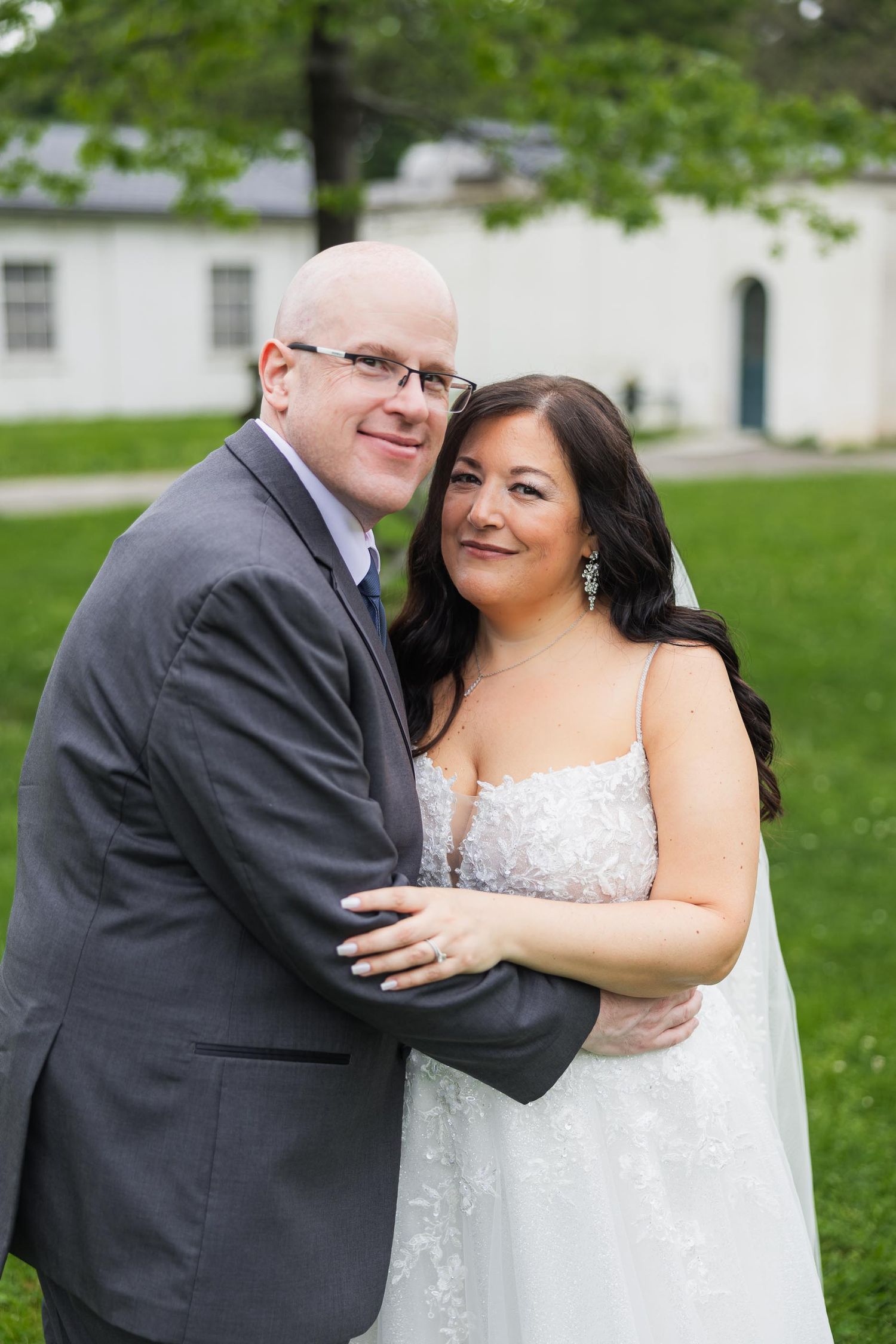 Romantic portrait of newlyweds embracing on green lawn.