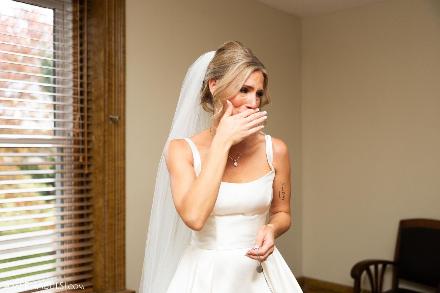 Candid emotional moment captured during wedding preparations by a window.