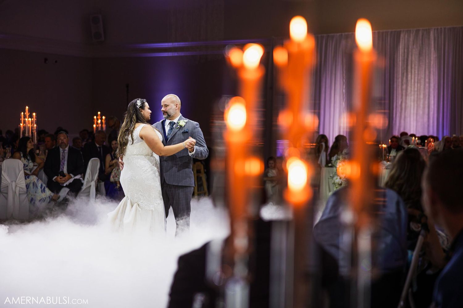 Romantic first dance at wedding reception with fog and candlelight creating dreamy atmosphere.