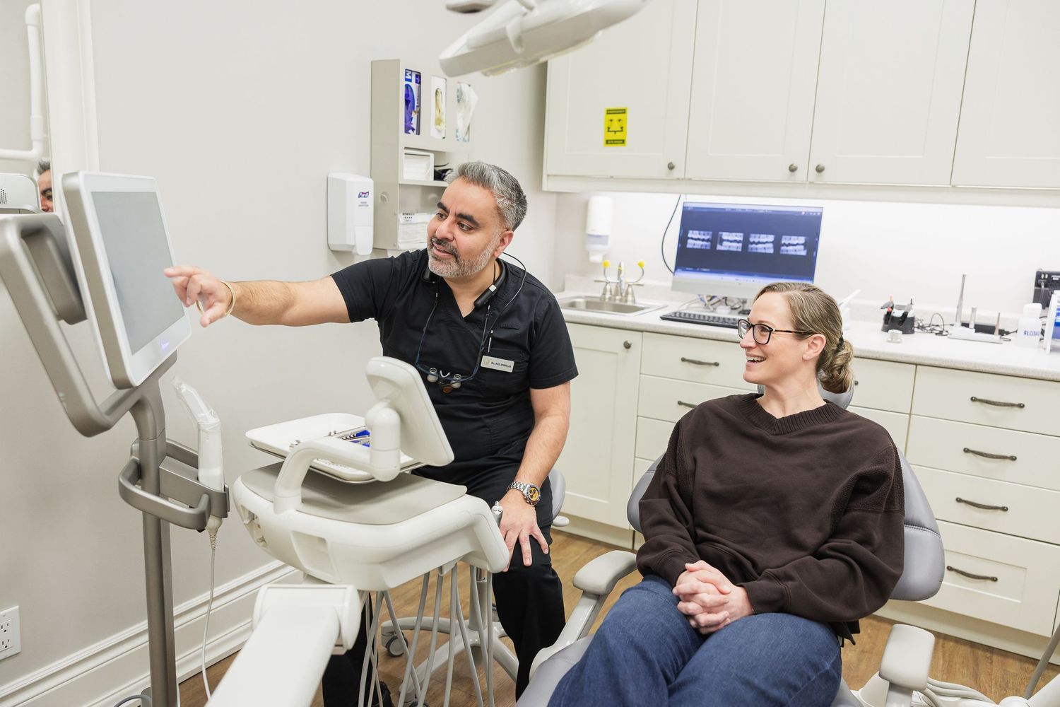 Dentist showing patient dental X-rays on monitor during consultation in modern dental clinic.