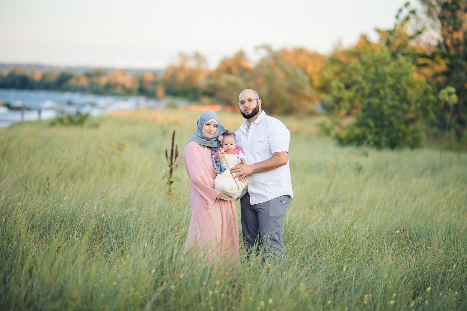 A couple embraces in a golden field during sunset creating a romantic outdoor portrait session.