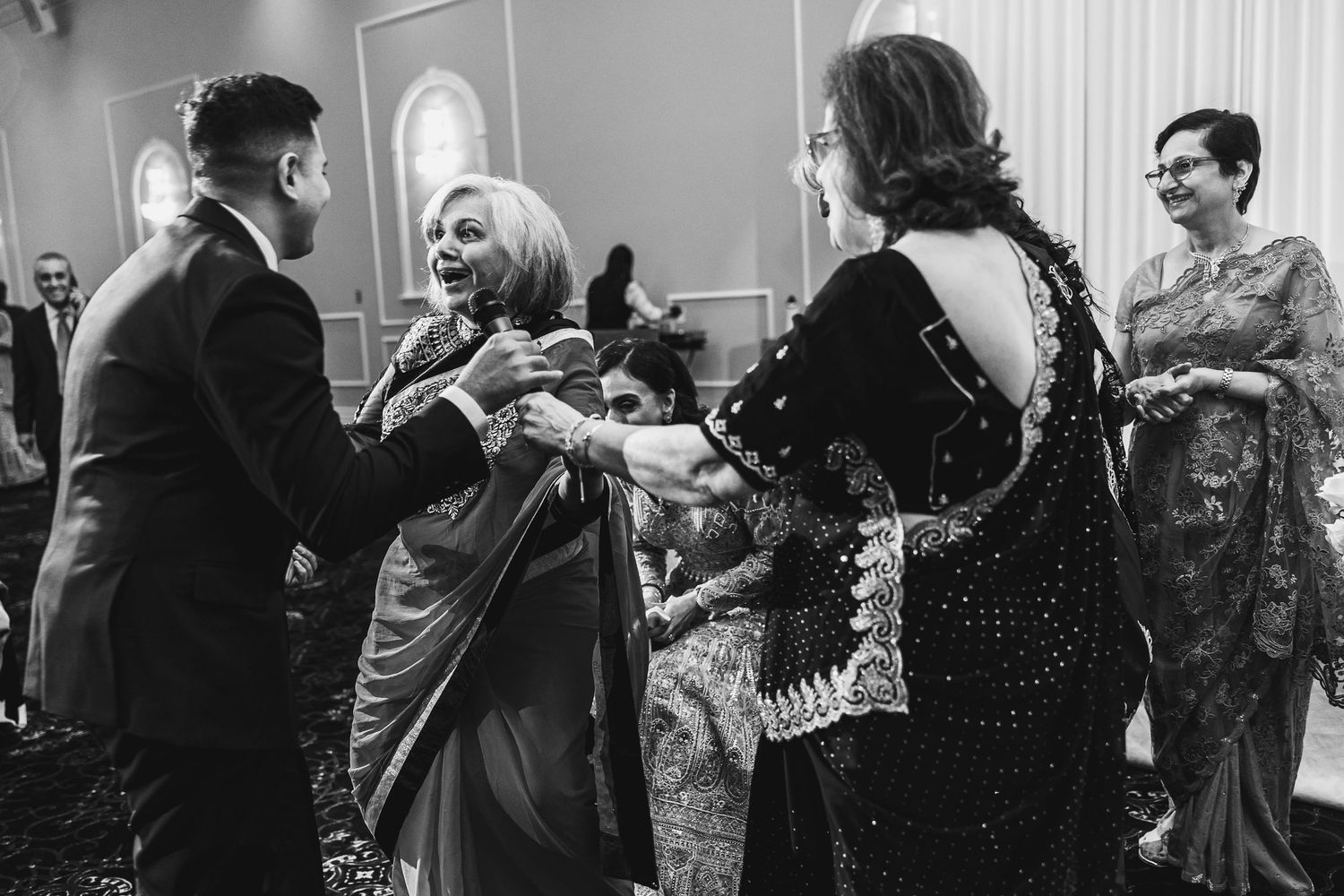 Wedding guests dancing and socializing at an elegant reception in black and white.