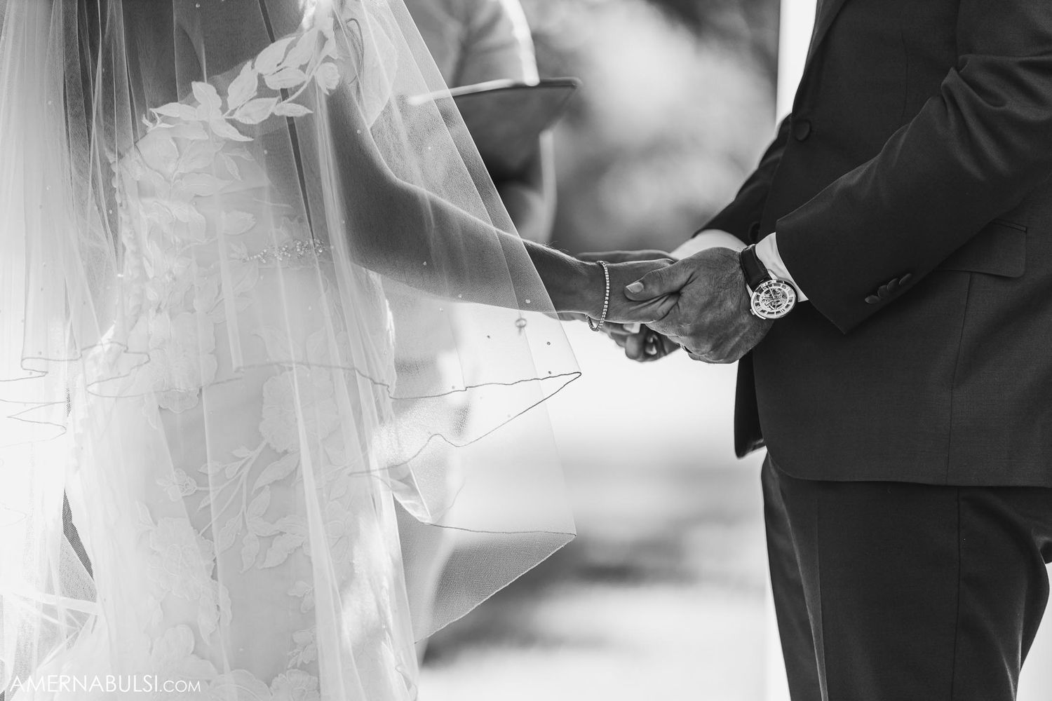 Close-up black and white photo of hands exchanging wedding rings during ceremony.