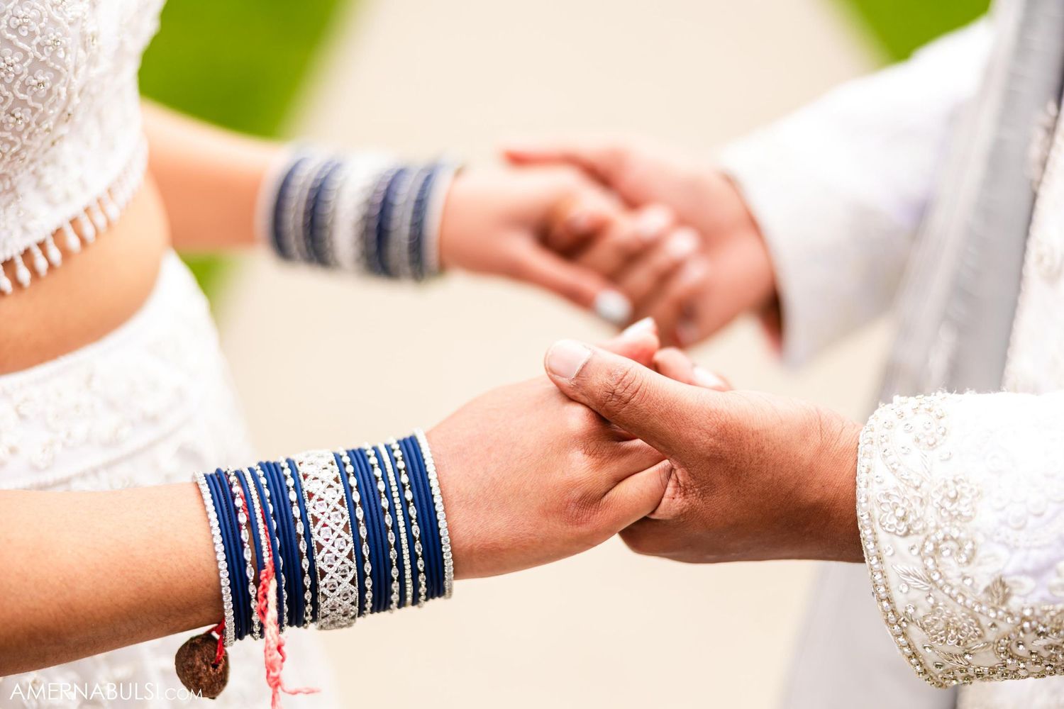 Close-up of hands with blue bangles during a wedding ceremony.