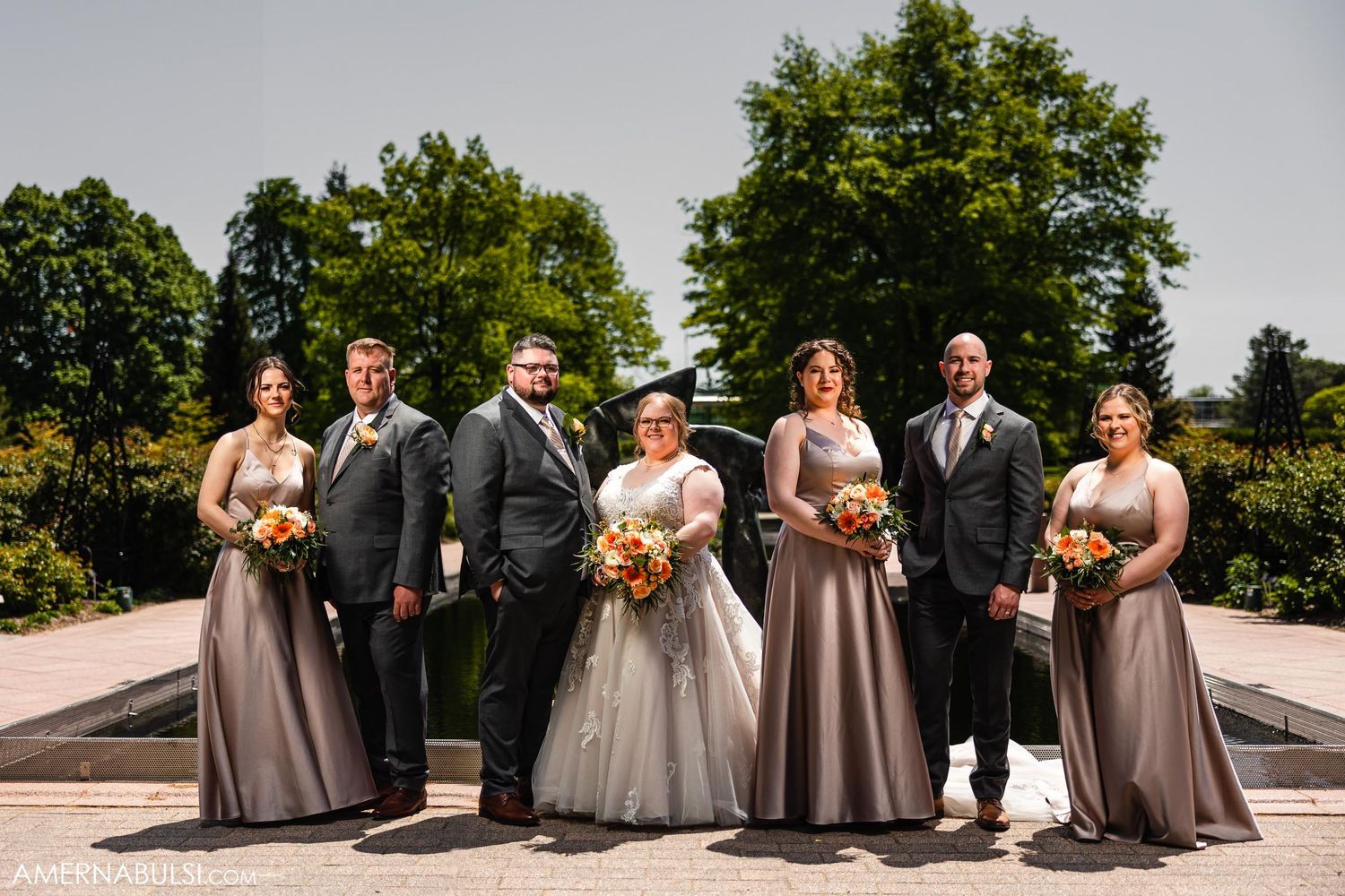 Wedding party poses outdoors in grey and neutral tones on a sunny summer day.
