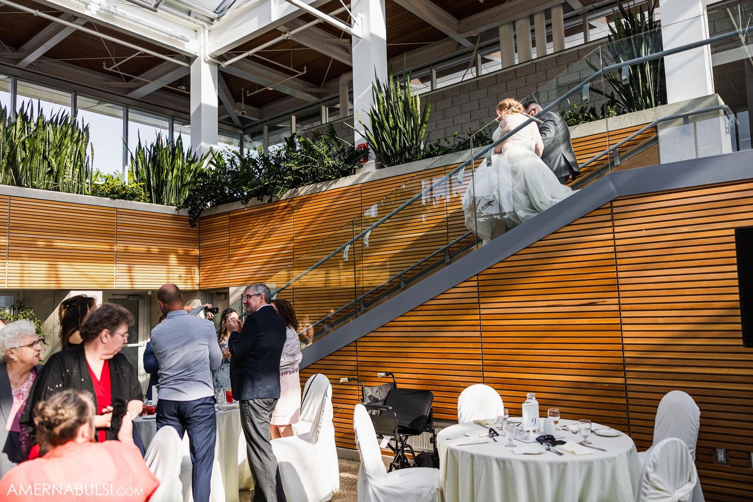 Wedding celebration on modern wooden staircase with guests gathering around tables.