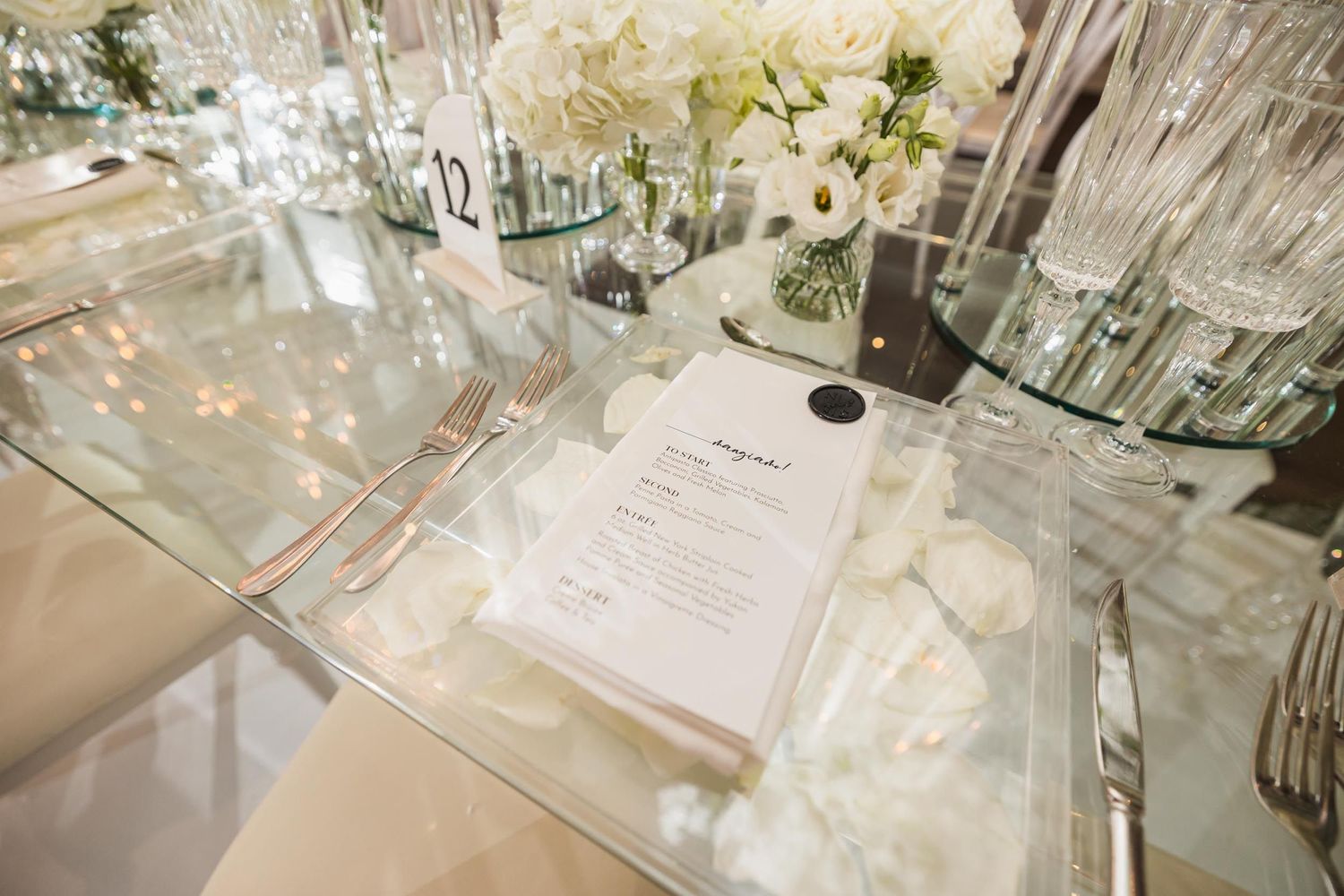 Wedding reception place setting with menu card and crystal glassware.