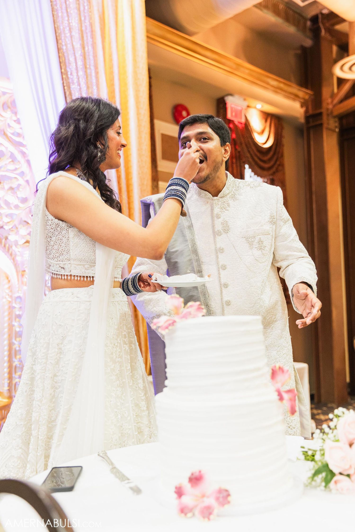 Bride feeds cake to groom in a playful moment at their wedding reception.