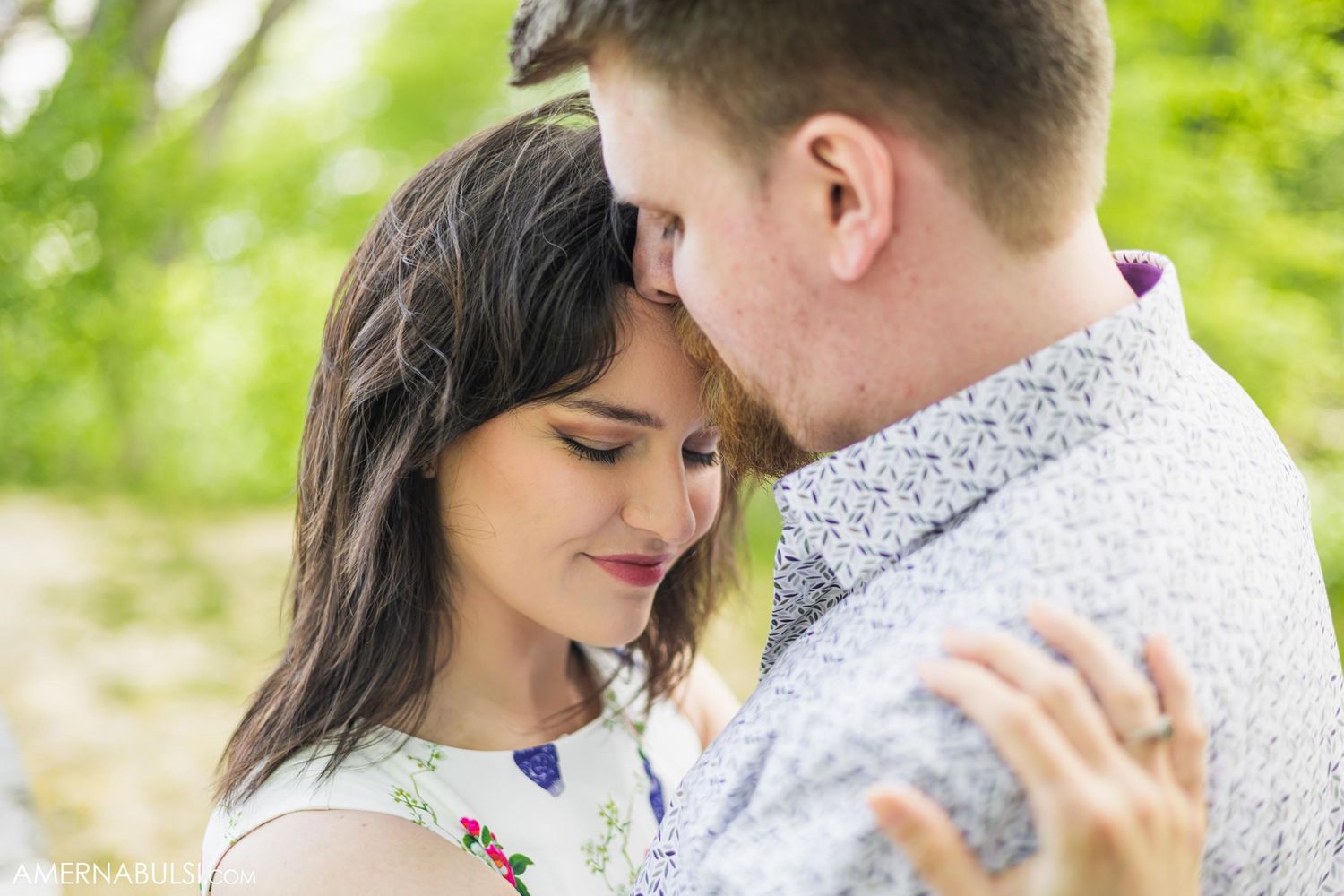 A romantic couple shares an intimate moment outdoors in a natural setting with soft lighting.