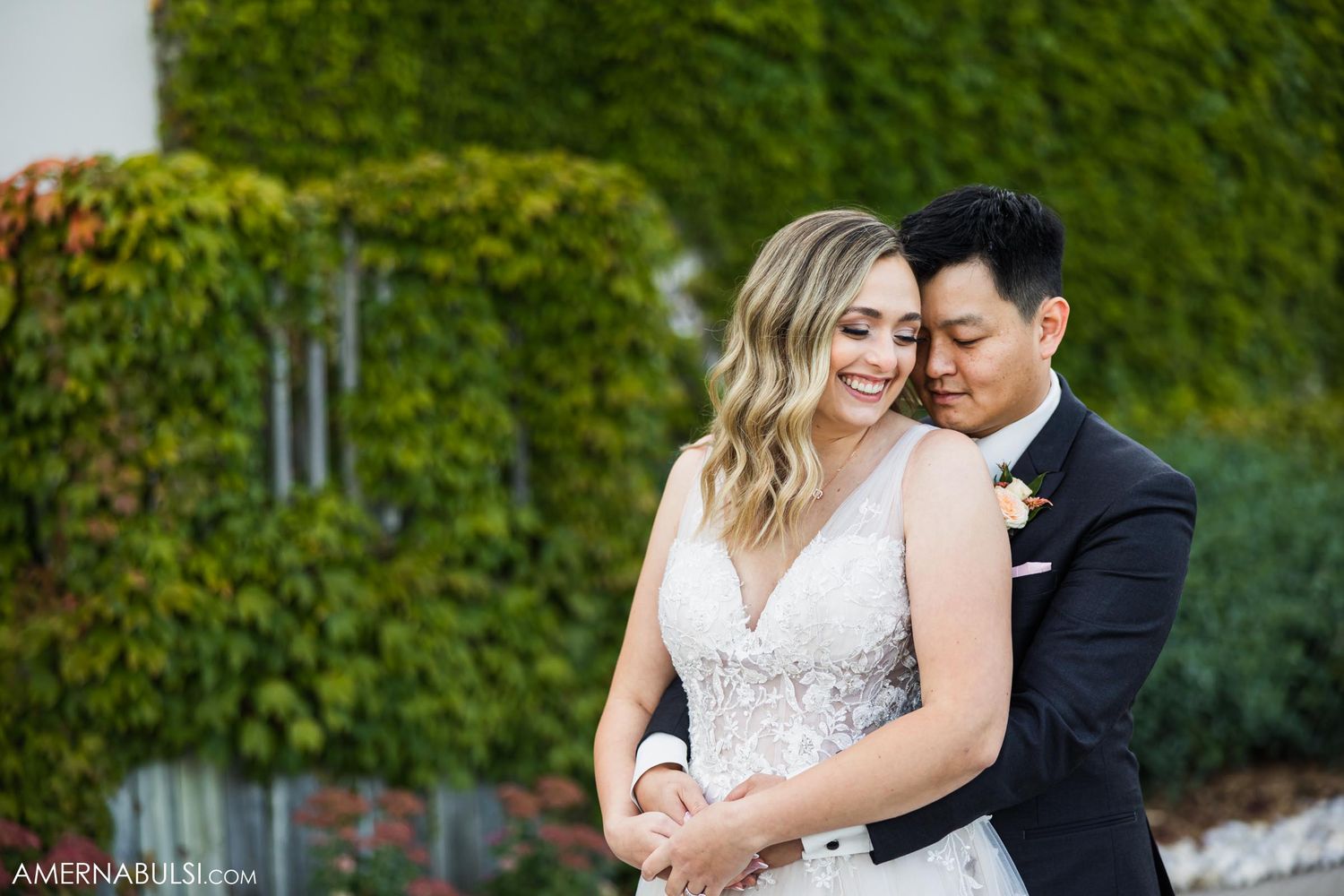 Romantic outdoor portrait of couple sharing intimate moment against ivy-covered wall.