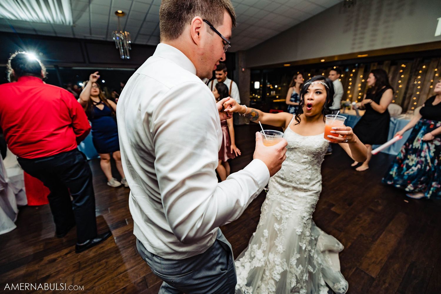 Couple dancing together on a wooden dance floor during reception celebration.