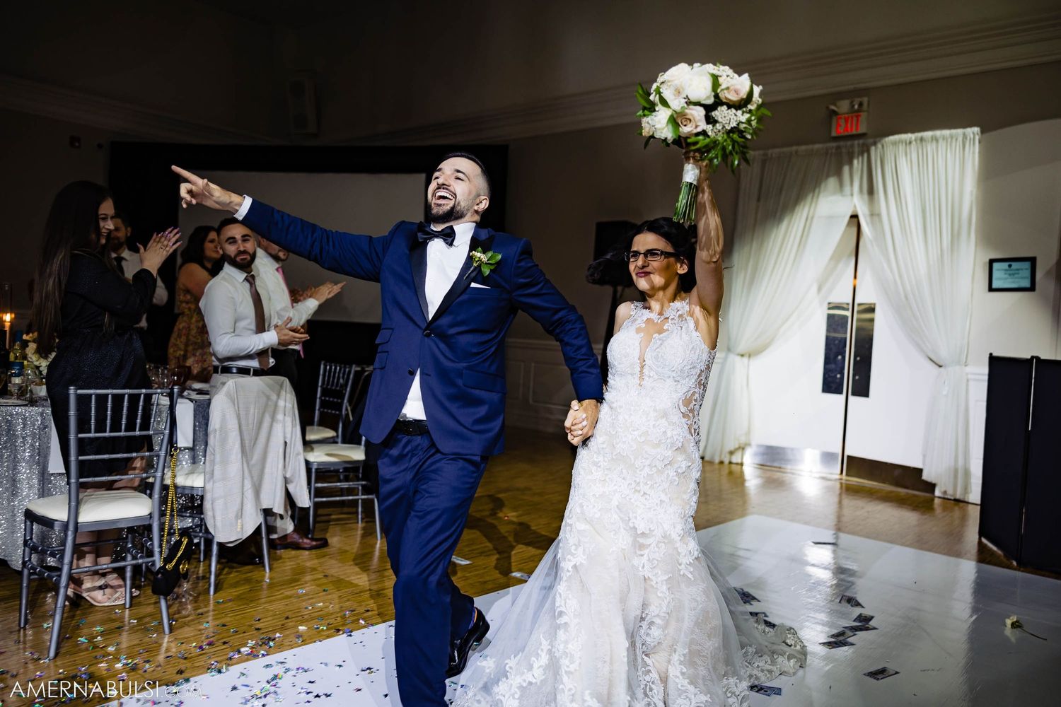 A celebratory entrance of newlyweds into their wedding reception with scattered flower petals on the floor.