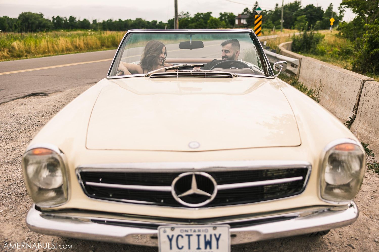 Front view of classic white Mercedes-Benz SL with chrome grill on country road.