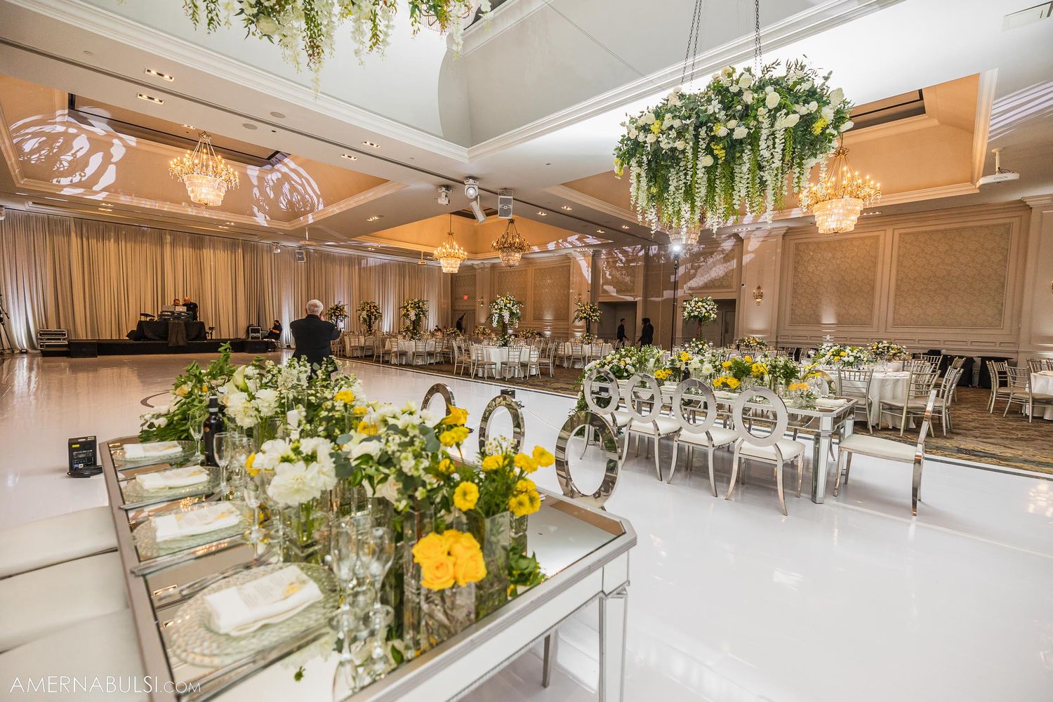 Opulent wedding reception room with crystal chandeliers and hanging greenery installations.