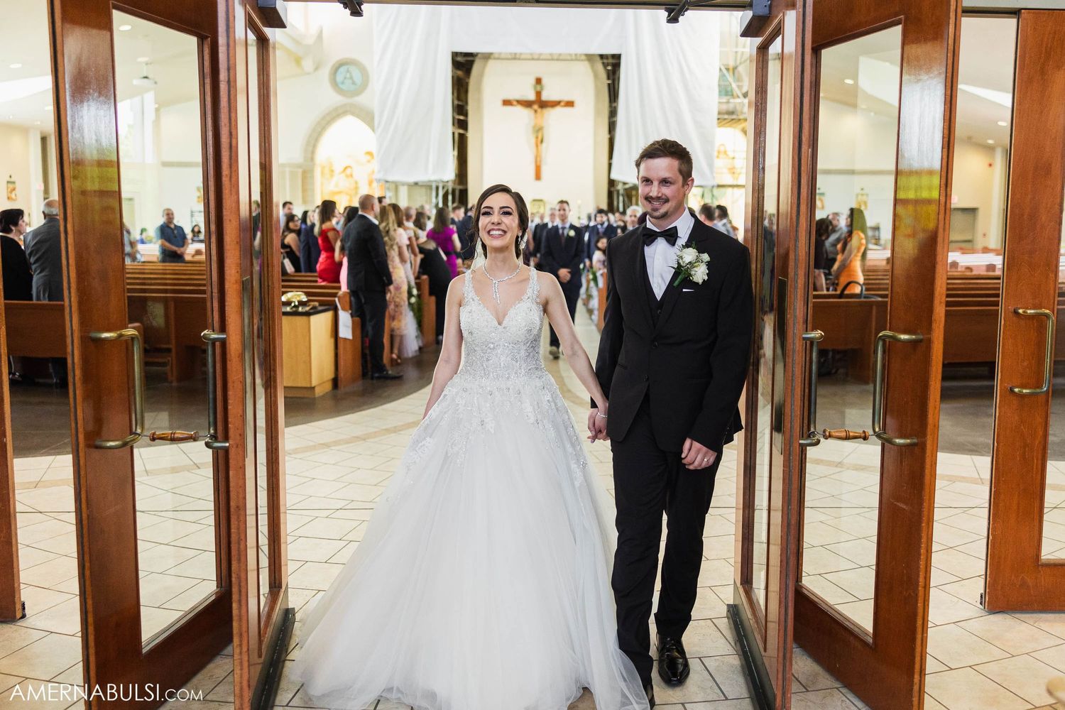 Newlyweds exit through wooden church doors after their ceremony.