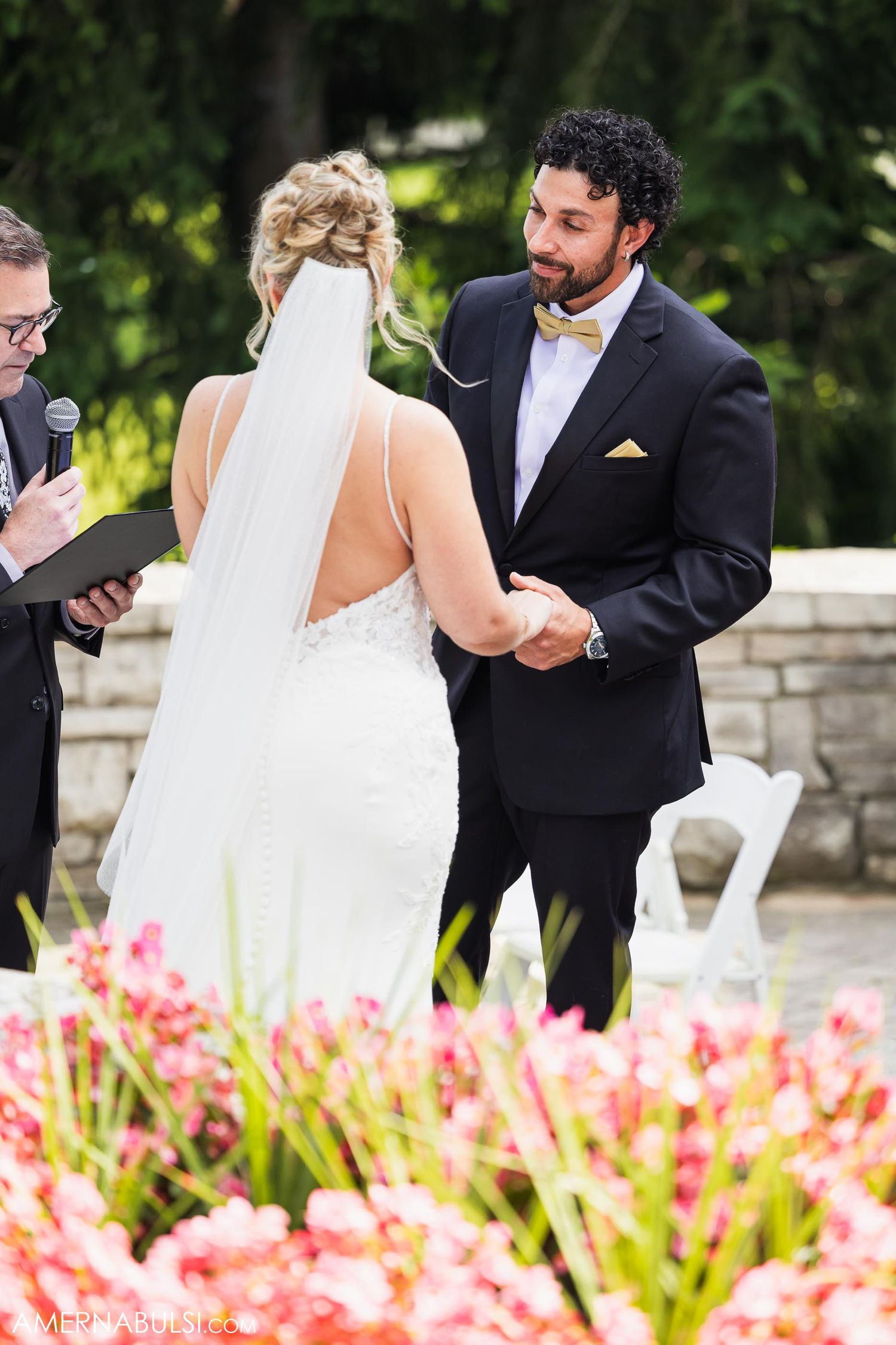 Wedding ceremony in a garden setting with pink flowers blooming in the foreground.