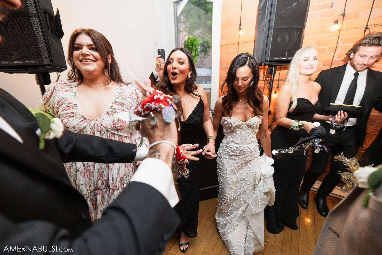 Wedding guests dancing and laughing together during a lively reception celebration.