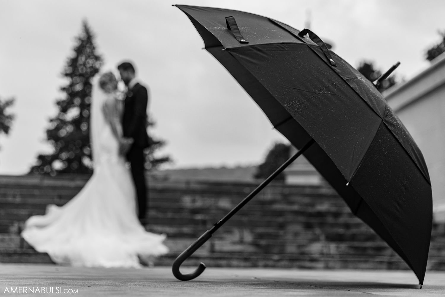 Black umbrellas create a dramatic silhouette against a cloudy sky.