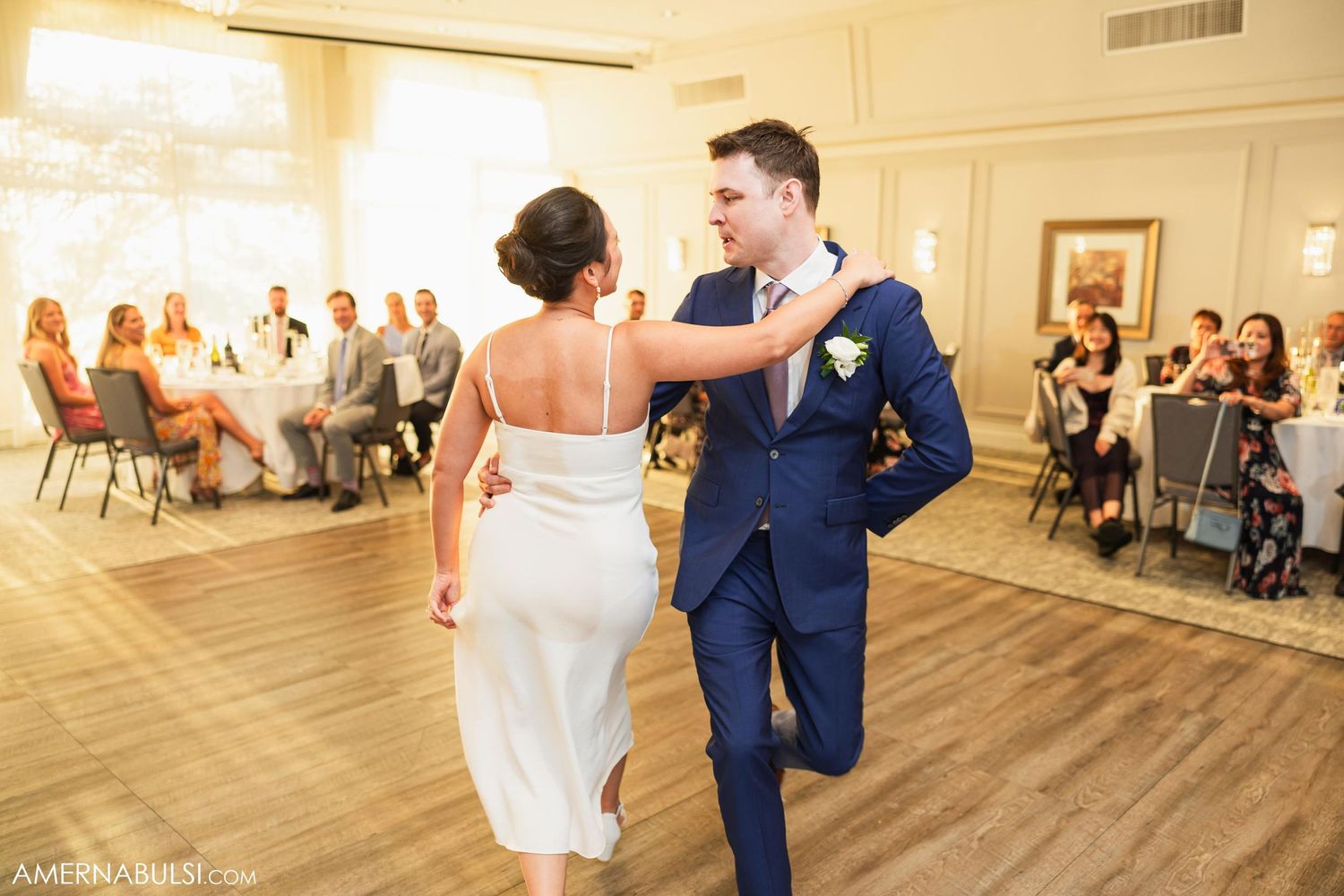 Wedding couple performs a fun dance routine while guests watch from tables in the ballroom.