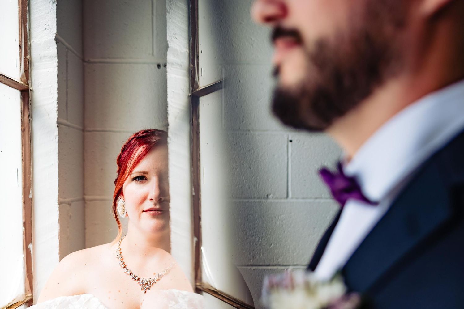 A close-up profile view of a couple in formal attire by a bright window.