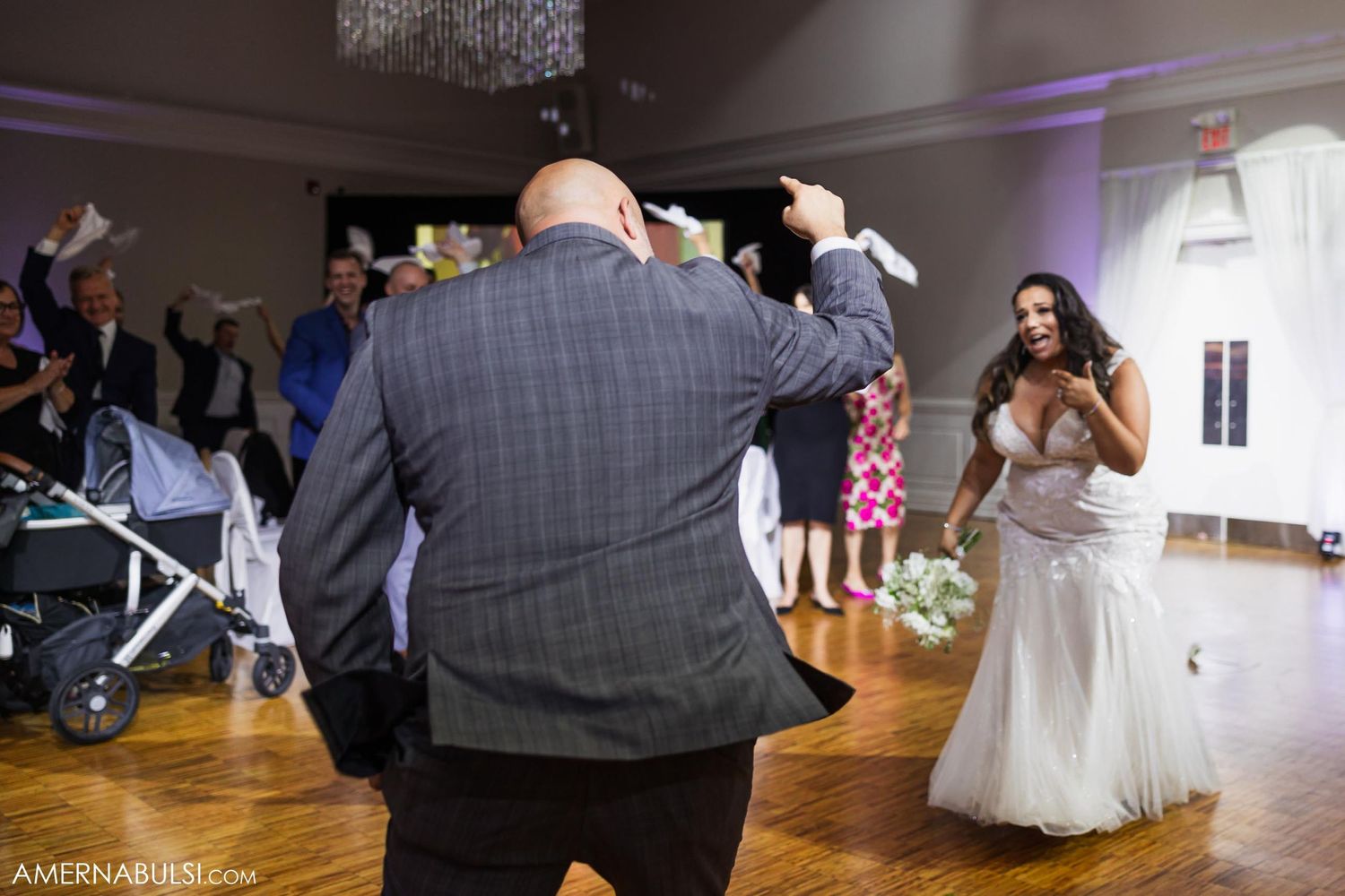Energetic dancing and interaction between wedding couple on wooden dancefloor with purple lighting.